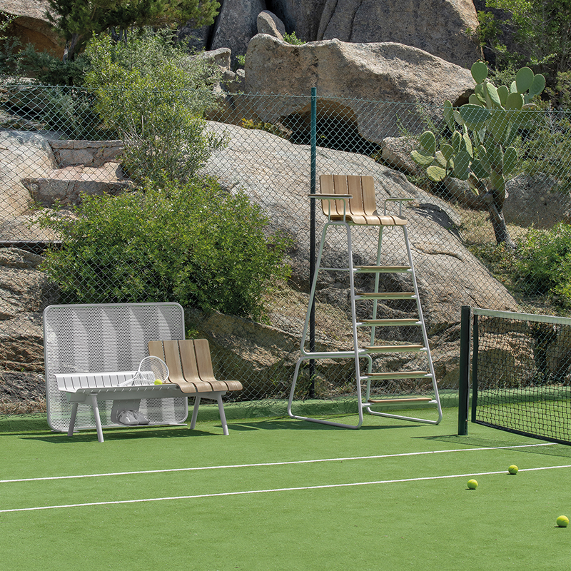 Cancha de tenis con silla de árbitro y banco de la colección Ace en un entorno deportivo al aire libre